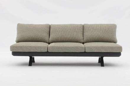 A cylindrical headrest with a light beige textured fabric cover is shown, attached to a black, U-shaped metal bracket.