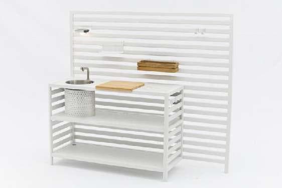 A white slatted outdoor kitchen unit with a sink, faucet, and wooden shelves, arranged in an L-shape.